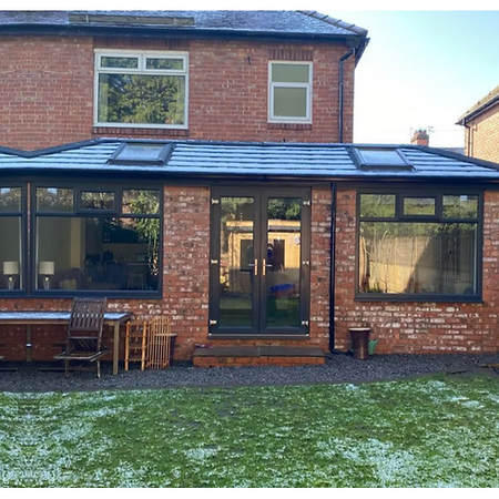 A red brick house extension with a sloped roof and skylights
