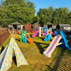 Outdoor play area with slides, teepees, and playhouses.