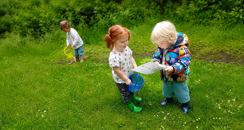 Three children exploring outdoors with buckets and a map.
