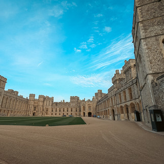Windsor Castle's large stone courtyard under a bright blue sky on a clear day.