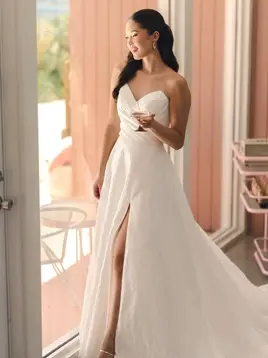 Smiling bride in strapless gown with high slit