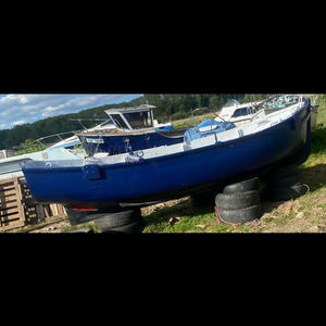 Blue 17-18 ft yacht on storage blocks outdoors.