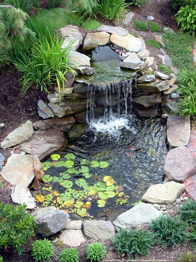 Limestone waterfall flowing into a pond with lilies