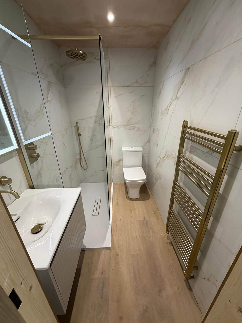 Modern bathroom featuring a glass walk-in shower with chrome fixtures and a towel neatly placed on a shelf.