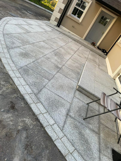 Grey paver driveway with curved border by house
