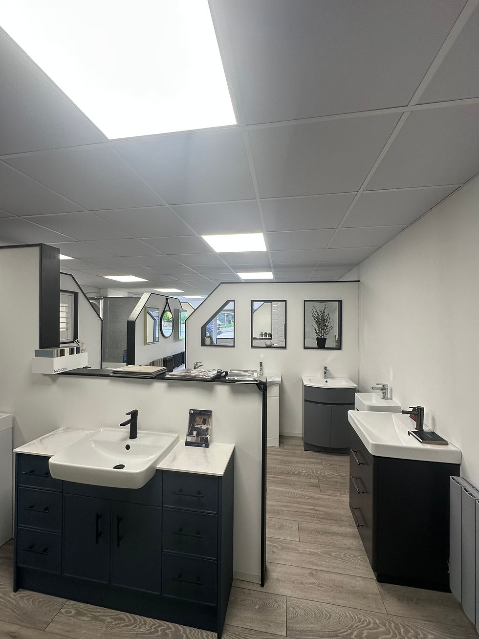 Modern bathroom showroom featuring a freestanding bathtub, glass shower, and sleek vanities with mirrors.