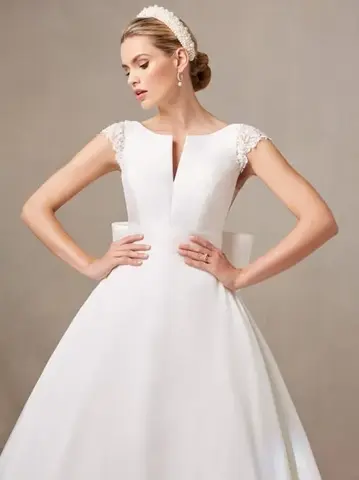 Bride in white wedding dress with cap sleeves and bow