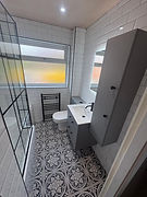 Modern bathroom with a freestanding tub, shower, wooden vanity, and a backlit mirror.