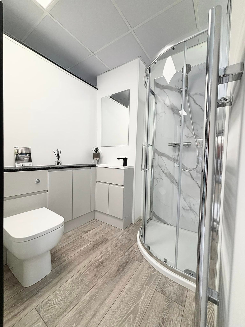 Three modern glass shower enclosures with sleek designs in a tiled bathroom setting.