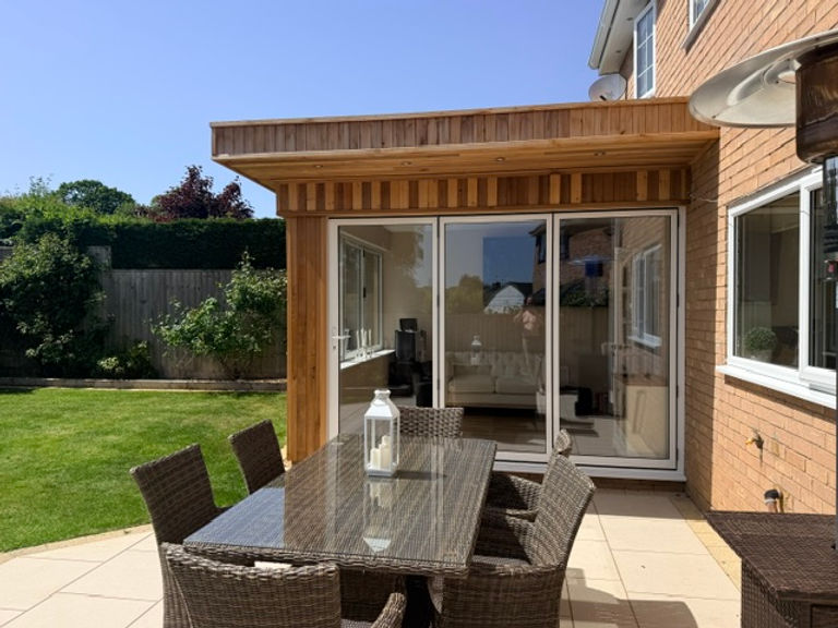 Wooden clad garden room with large glass doors and patio
