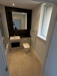 Modern bathroom with toilet, sink, mirror, and window