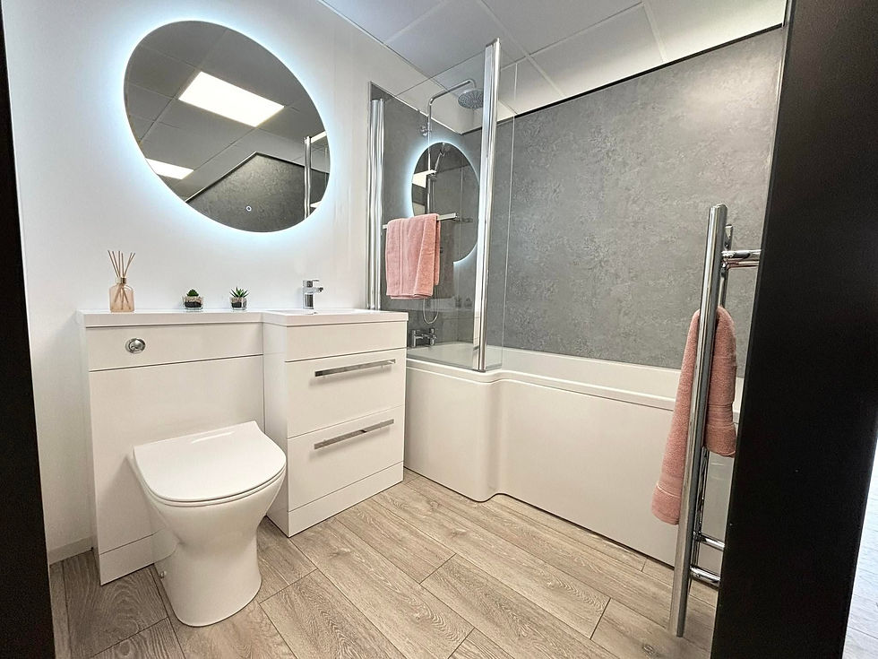 Modern bathroom with wooden vanity, wall-mounted mirror, toilet, and a sleek bathtub with a glass shower screen.