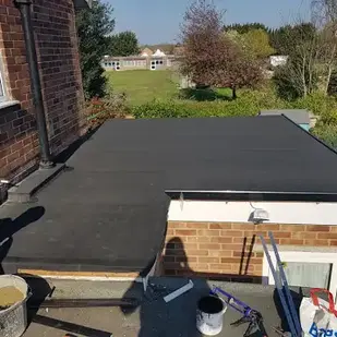 New flat roof installation on a brick building with green background