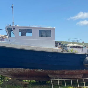 Small 17 - 18 ft yacht with blue hull on dry dock.
