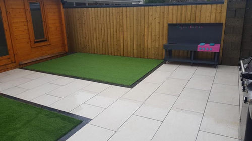 Patio with artificial grass, wooden shed, and fence