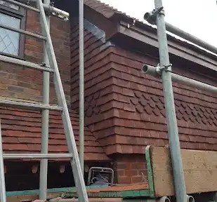 Brick house siding construction with scaffolding, ladder, and a window in progress.