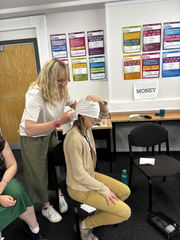 Woman bandages another woman's head in a room with