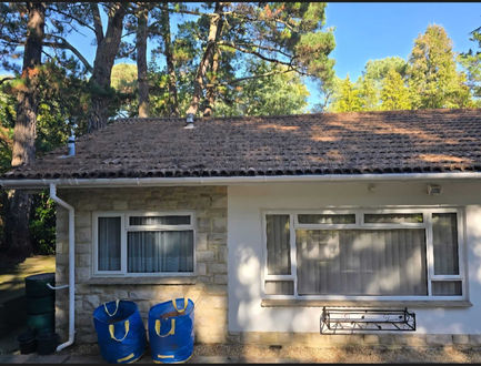 Roof cleaning completed on a white house with a brown tiled roof.