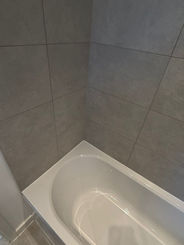 White bathtub with tiled walls