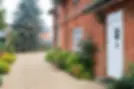 Brick house with white door, gravel driveway, and garden