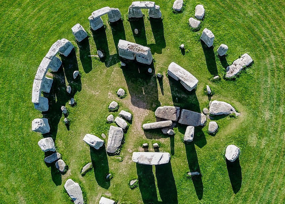 Aerial view of Stonehenge; large stone circle on green grass, casting long shadows. Clear day, ancient and mysterious mood.