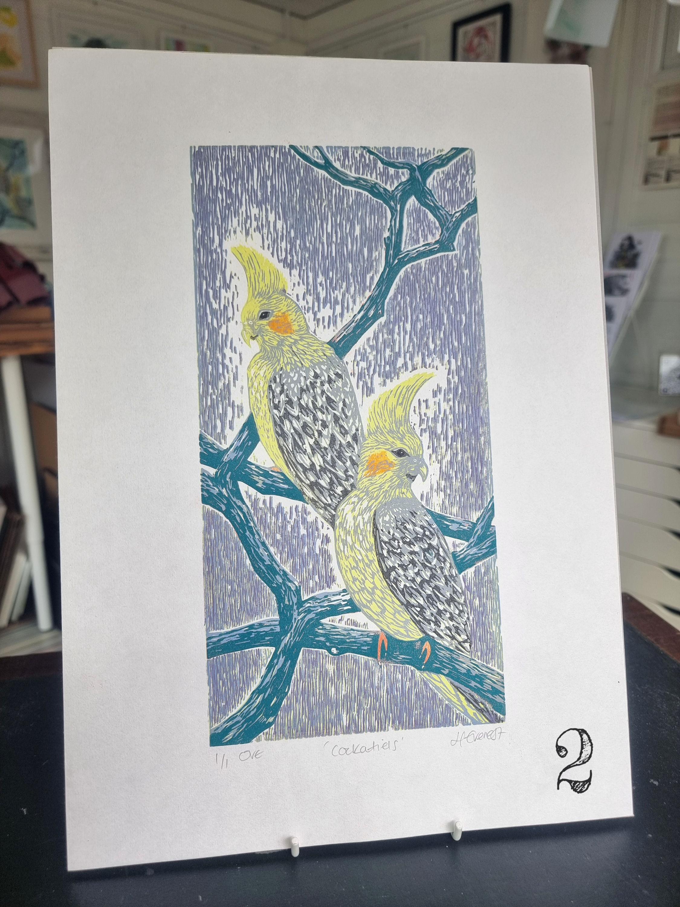 Cockatiels is an original linocut print featuring two pearl cockatiels perched on a branch.