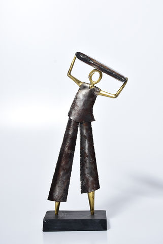 Escultura em metal de um estivador carregando uma saca sobre a cabeça, série Cotidiano e Resistência. Obra em ferro e latão que faz referência histórica à Ladeira da Preguiça e à força dos trabalhadores negros no Brasil Colonial.
