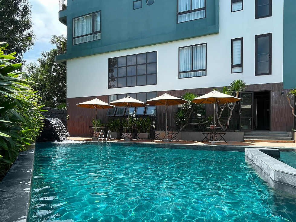 Hồ bơi ngoài trời xanh ngọc bích mát lạnh tại khu nghỉ dưỡng, với kiến trúc hiện đại và không gian xanh bao quanh.