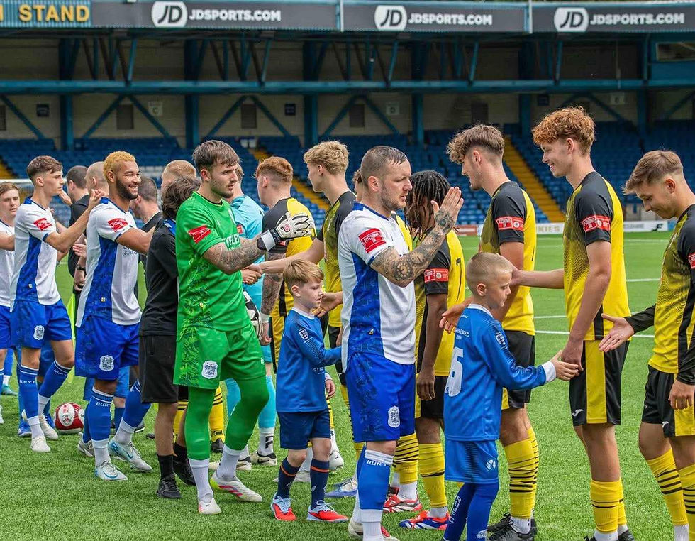 Newcastle Town and Bury players exchange handshakes at Gigg Lane ahead of the Northern Premier League fixture on Saturday 9th August 2025