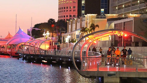 Evening view of the Tampa Riverwalk with its illuminated canopy walkway, waterfront skyline, and colorful lights — a top Tampa attraction highlighted by Luxury STR Cleaners for Airbnb and vacation rental guests.