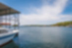 A view from a dock on Lake Hartwell looking out to another marina and the lake. The bow of a speedboat parked at a dock is at the left of the image.