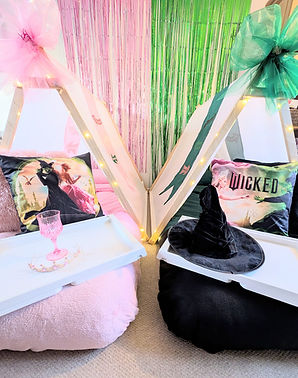 Decorated indoor seating area with two small teepee-style frames draped in pink and green tulle bows and fairy lights.