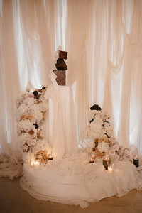 stacked brown marble effect wedding cake agaisnt a draped wedding ceremony area