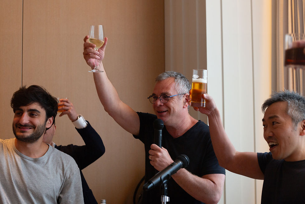 室内で、数人が乾杯している。手にビールやワイングラスを持ち、楽しそうな表情。明るい壁に囲まれた会場。