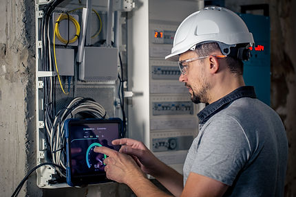 man-electrical-technician-working-switchboard-with-fuses-uses-tablet.jpg