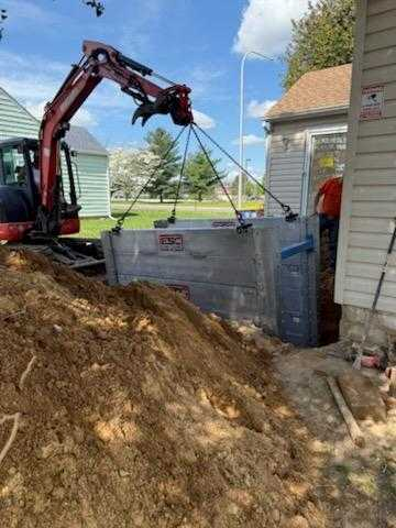 ESC aluminum modular trench box being installed in a residential utility excavation using a compact excavator, providing safe trench protection in a confined jobsite.
