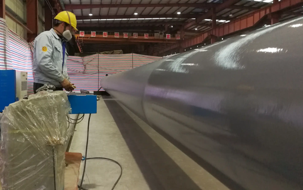 Application of corrosion protection coating on a steel pipe pile inside a fabrication facility, enhancing durability and long-term performance for marine, offshore, and infrastructure projects.