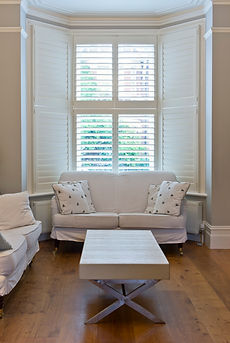 bay window of white shutters middle one is open