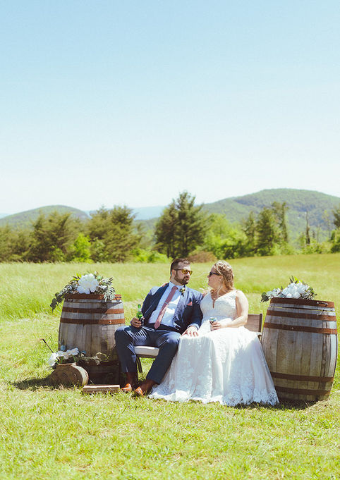 Couple sitting on whiskey barrels with 180° mountain views near Edneyville, NC, at a wedding venue