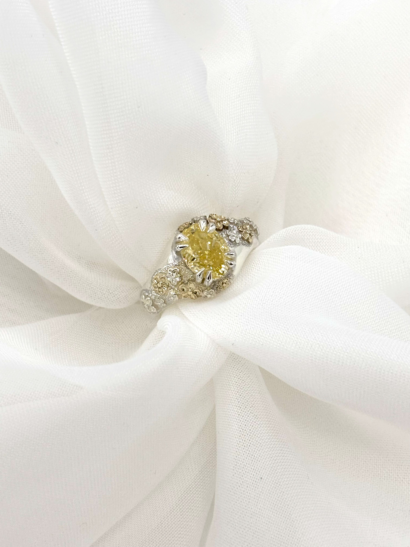 A handcrafted sterling silver ring with delicate yellow gold cherry blossoms and a vivid yellow diamond center piece.