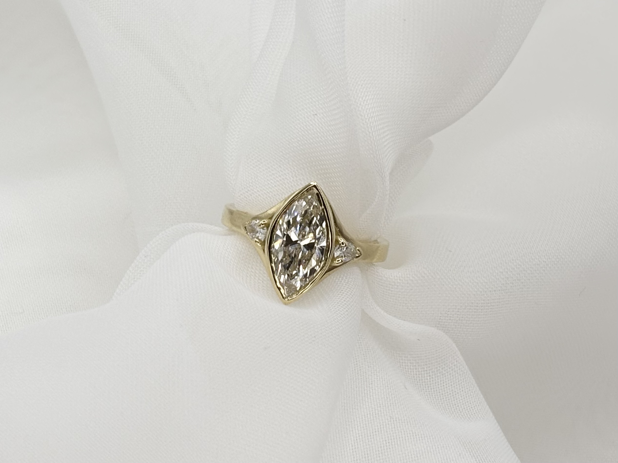 A master craftsman meticulously working on a gold engagement ring with diamonds in a workshop environment.