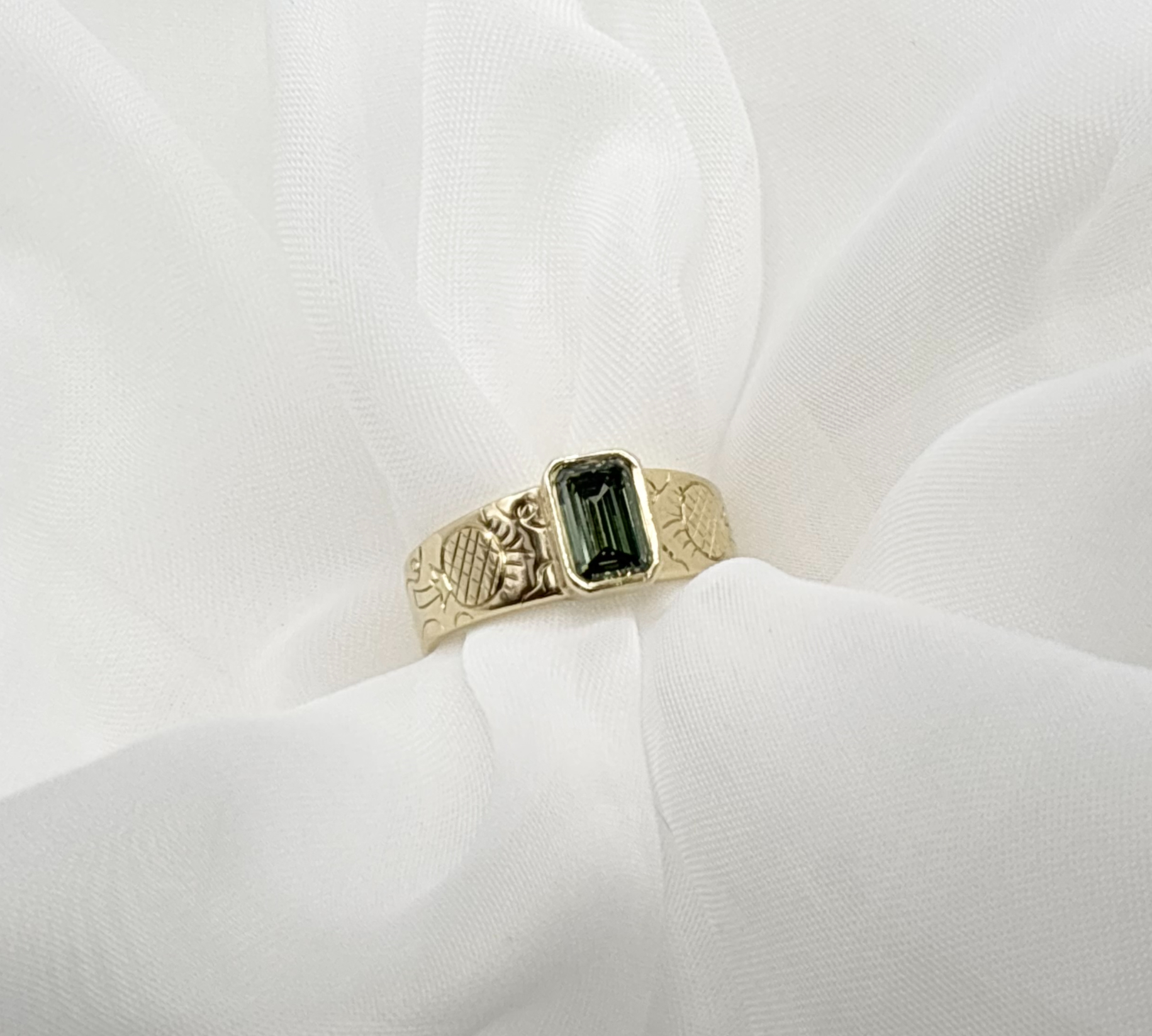 A close-up of a delicate 18ct gold ring setting on a jeweller's workbench.