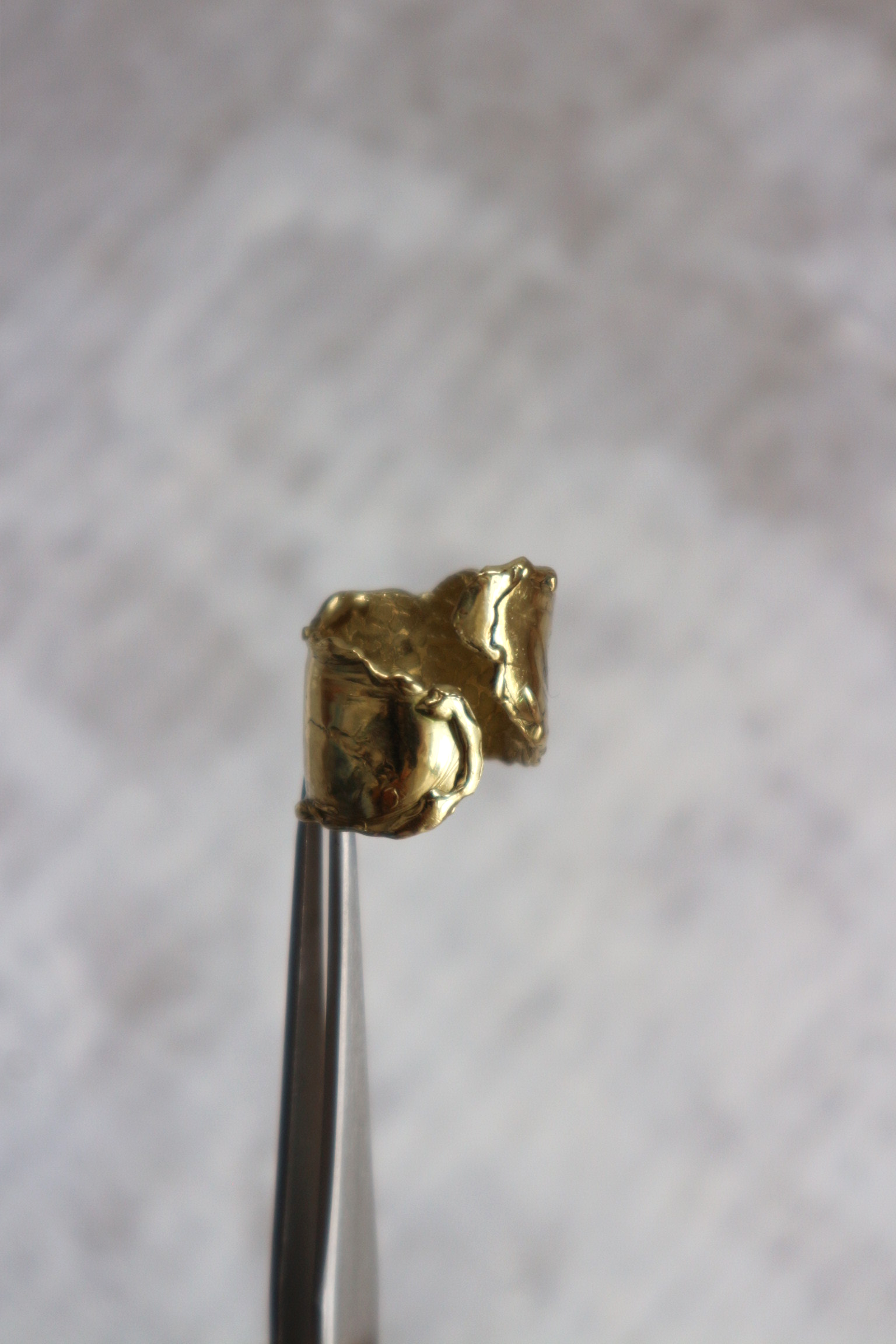 detail front view of handcrafted wave inspired brass ring