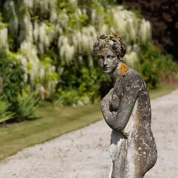 A close up of a single stone statue of a woman one of several lining this path
