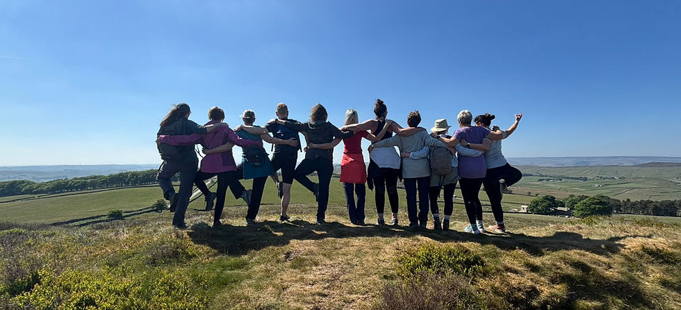 Group of people standing on a hill, arms linked, practicing yoga. Friendship and wellbeing.
