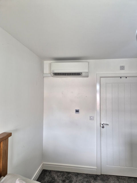 An air conditioning unit attached to an internal wall, sited next to a door. 