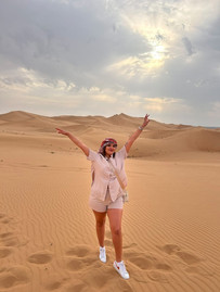 a woman standing with arms up in the desert