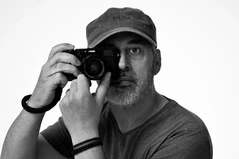 Homme avec une casquette, il y a un appareil photo devant le visage, image sur fond blanc en noir et blanc, studio Paris.