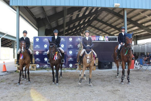 A group of Belle Wood Equestrian riders proudly displaying their awards and ribbons.