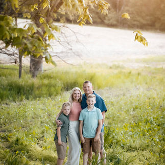 family smiles on their farm land during family photos in Omaha, ne